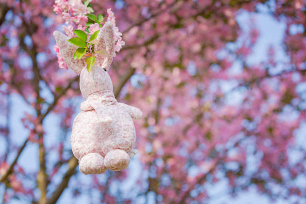 istock Rabbit doll hanging on a Begonia flower, background is pink 939099142