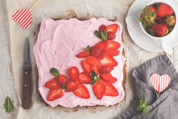 istock St.Valentine's Day Cake for breakfast with pink glaze and fresh strawberries. Light background, summer dessert. Top view, copy space. 939107258