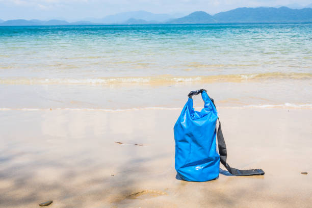 Blue waterproof bag on the beach with seascape background. stock photo