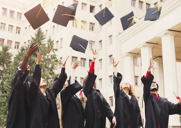 istock A group of graduates throwing graduation caps in the air 939111438