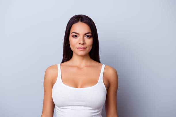 portrait d’une jeune fille de latino américain. elle est dans un classement de casual singulet blanc sur le fond bleu clair pur - marcel photos et images de collection