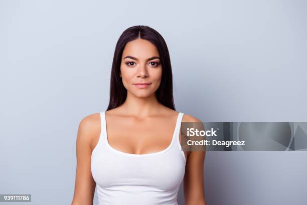 Portrait Of A Young Latino American Girl She Is In A Casual White Singlet Standing On The Pure Light Blue Background Stock Photo - Download Image Now