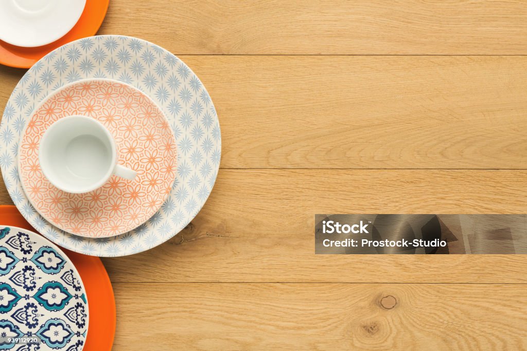 Empty vintage plates and coffee cup on natural wood, top view Set of empty colorful vintage plates and black coffee cup, top view on natural wood. Table setting and tableware concept Crockery Stock Photo