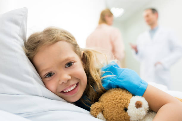 istock happy kid lying on hospital bed while mother talking with doctor 939116644
