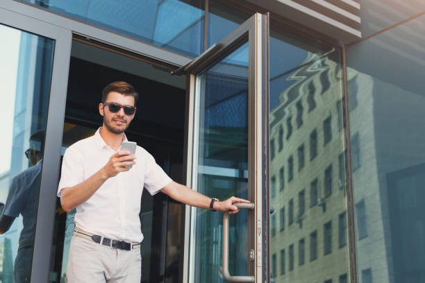 istock Dreamy handsome businessman leaving building and using phone 939117070