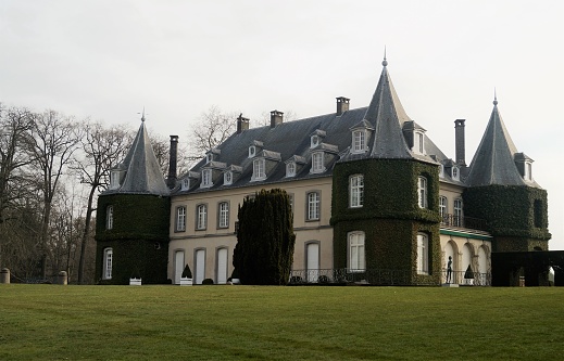 La Hulpe, Belgium - March 26, 2018: The Chateau de La Hulpe is a 19th-century French style castle in the Wallonia province of southern Belgium outside Brussels. The château was completed in 1842 in Flemish Neo-Renaissance style, flanked by towers at each of the four corners. In the late 19th century, the house and estate were acquired by Ernest Solvay.
