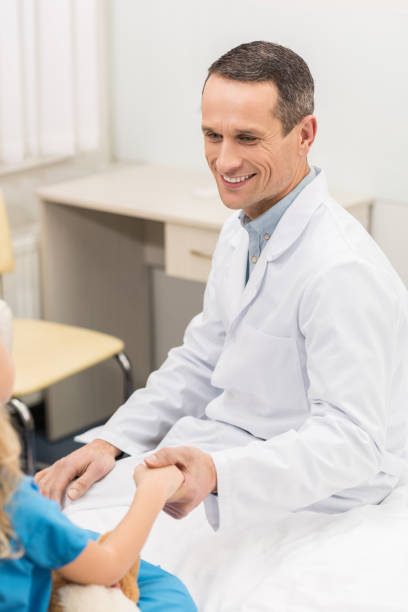 istock smiling doctor holding hands with kid patient 939125298
