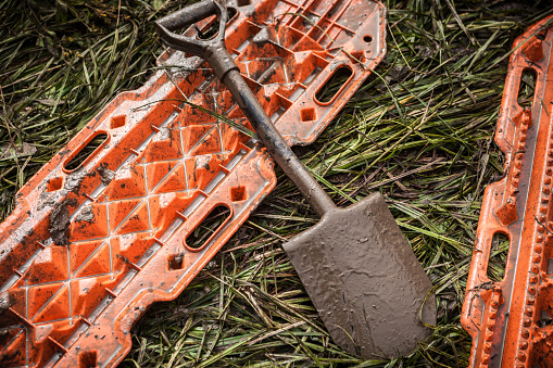 Orange rescue sand tracks and shovel on grass - offroad recovery equipment.