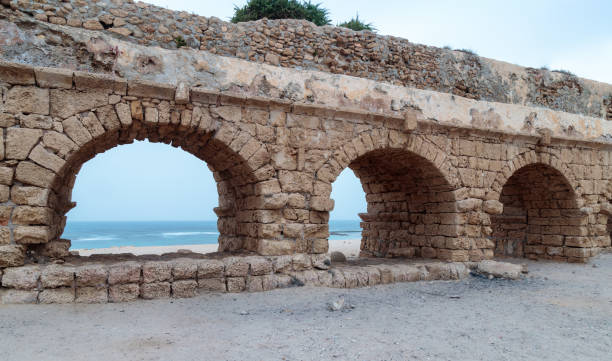 остатки древнеримского акведука на побережье средиземного моря возле города кесарии в израиле - caesarea стоковые фото и изображения