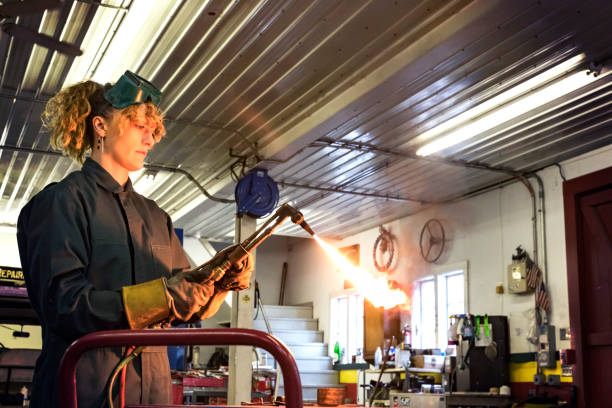 Female mechanic operating a blow torch.