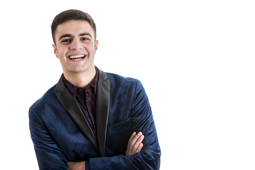 Confident young man smiles cheerfully at the camera. Photo is taken in front of a white background.