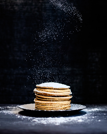 Stack of pancakes with an icing sugar swirl with a dark background