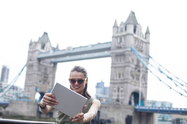 istock Young woman taking selfie with tablet on Tower bridge 939133372