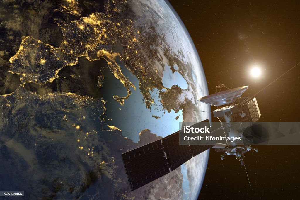 un satélite orbitando la tierra con las ciudades iluminadas en la noche - Foto de stock de Satélite libre de derechos