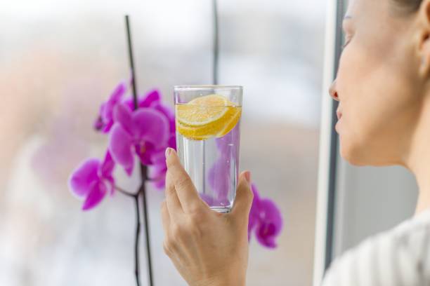 istock Woman drinking summer refreshing fruit flavored infused water with fresh organic lemon 939144448