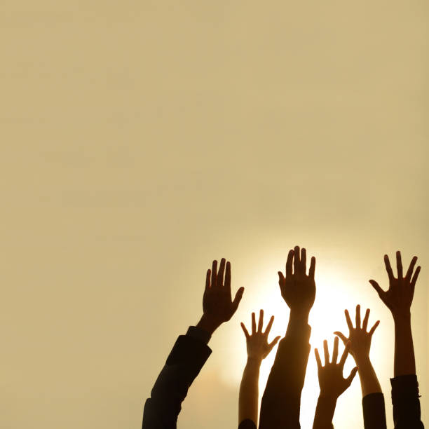 istock silhouette of  diverse people hands rised up on hot light background 939145360