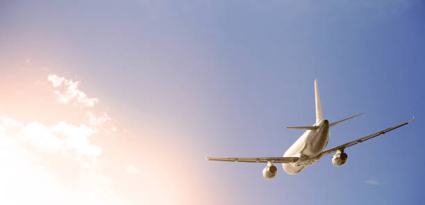 istock Airplane is flying past clouds in a blue sky 939145510