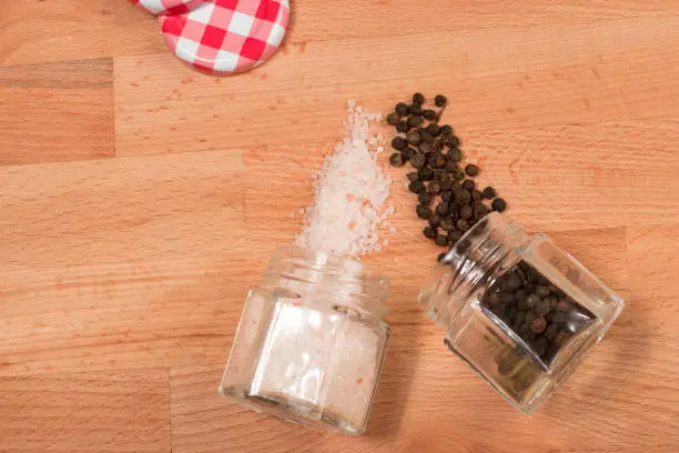 salt and pepper in jar on a wooden background