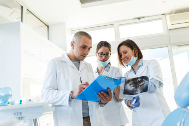 istock Group of dentists examining x-ray image of patients teeth. 939148918