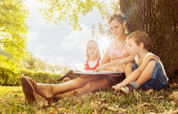 istock Young mother with son and daughter reading book 939149474