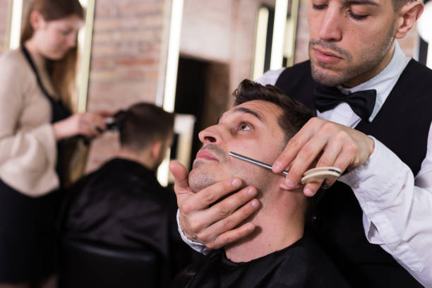 istock Barber shaving client with straightl razor 939152986