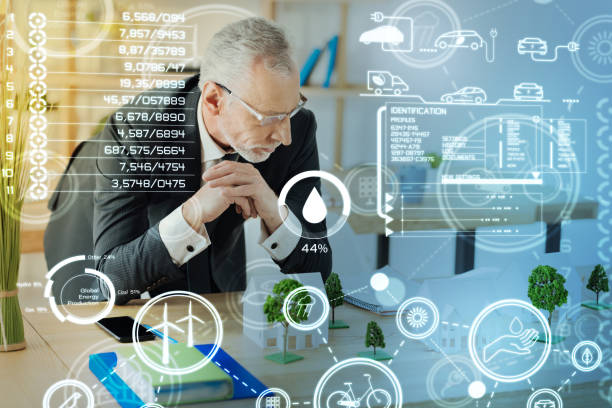 istock Serious mature engineer leaning to the table and looking at the miniatures 939155410
