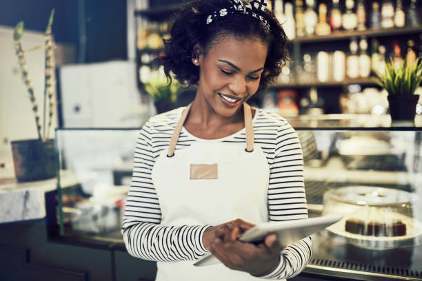 istock Smiling African cafe owner working with a digital tablet 939159648