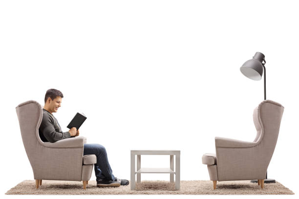 istock Young man sitting in an armchair and reading a book 939160478