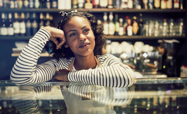 Young African entrepreneur leaning on her cafe counter thinking