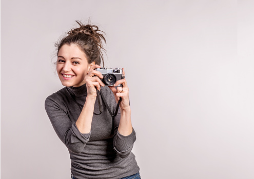 Portrait of a young beautiful woman holding a camera in studio. Copy space.