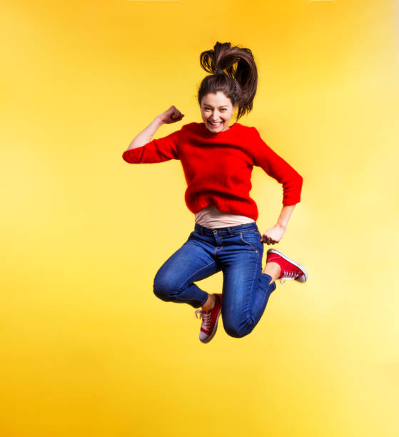 istock Young beautiful woman in studio, jumping on yellow background. 939169094