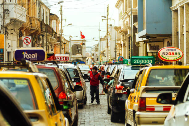 imagem diária. uma criança oferece para limpar os para-brisas dos carros para taxistas em um engarrafamento no centro da cidade de arequipa - 5891 - fotografias e filmes do acervo