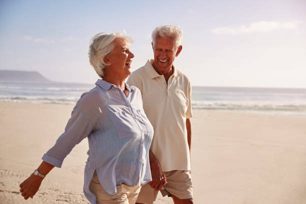 istock Senior Retired Couple Walking Along Beach Hand In Hand Together 939174148