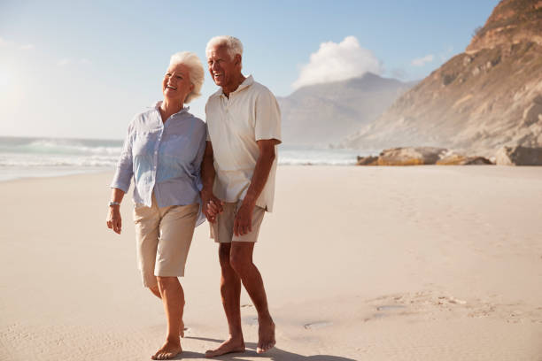 istock Senior Retired Couple Walking Along Beach Hand In Hand Together 939174158