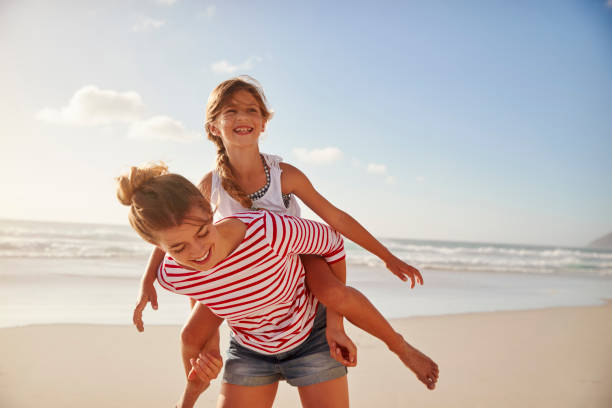 istock Mother Carrying Daughter On Shoulders On Beach Vacation 939177806