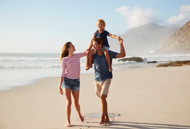 genitori che portano il figlio sulle spalle durante le vacanze al mare - family beach cheerful happiness foto e immagini stock