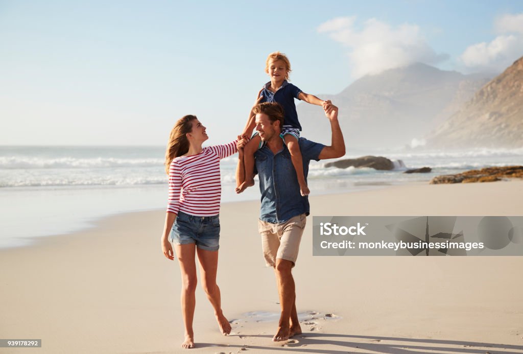 Parents Carrying Son On Shoulders On Beach Vacation Family Stock Photo