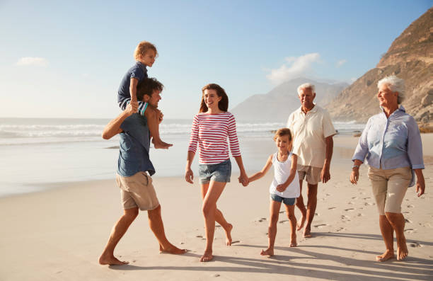 istock Multi Generation Family On Vacation Walking Along Beach Together 939179966