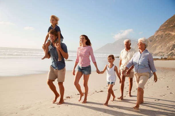 istock Multi Generation Family On Vacation Walking Along Beach Together 939180704