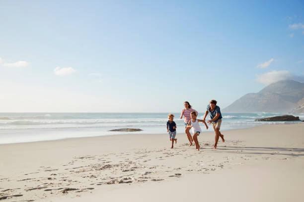 parents running along beach with children on summer vacation - family beach cheerful happiness imagens e fotografias de stock