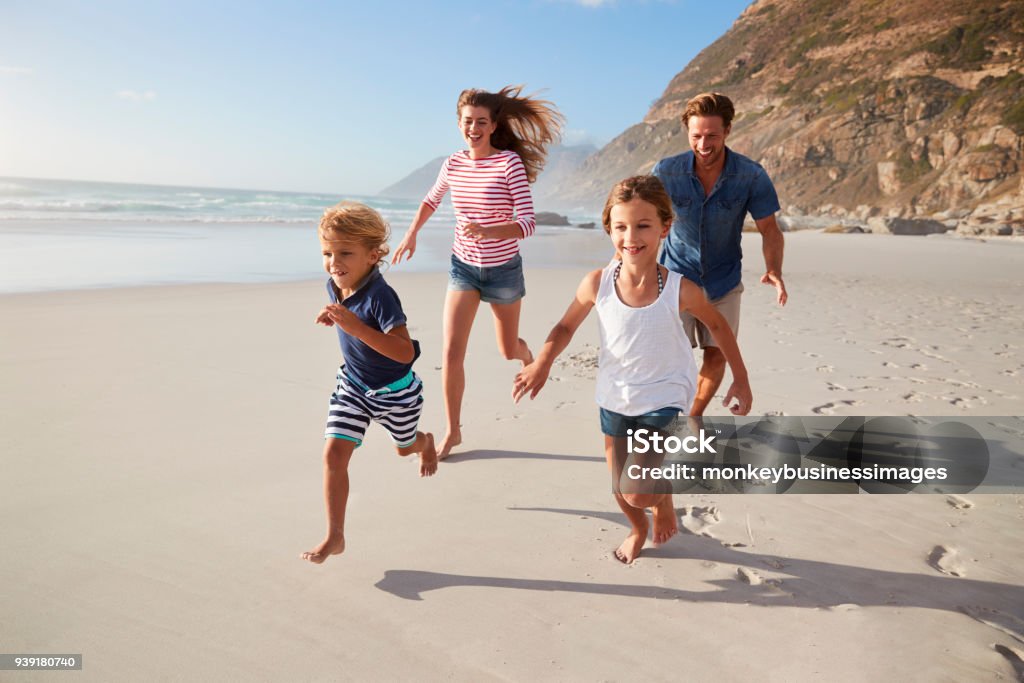 Padres que corre a lo largo de la playa con los niños en vacaciones de verano - Foto de stock de Familia libre de derechos