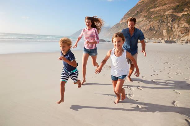 istock Parents Running Along Beach With Children On Summer Vacation 939180740