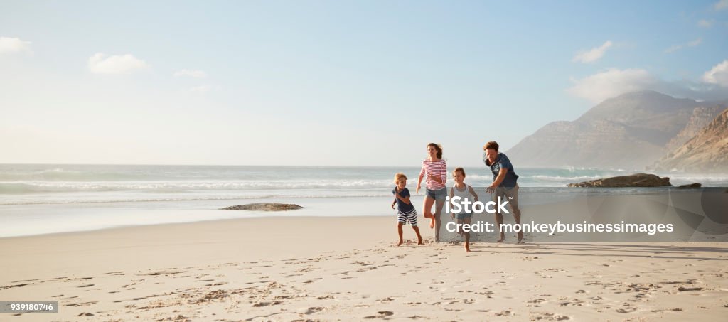 Padres que corre a lo largo de la playa con los niños en vacaciones de verano - Foto de stock de Familia libre de derechos