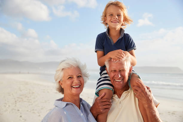 istock Grandparents Carrying Grandson On Shoulders On Walk Along Beach 939180876