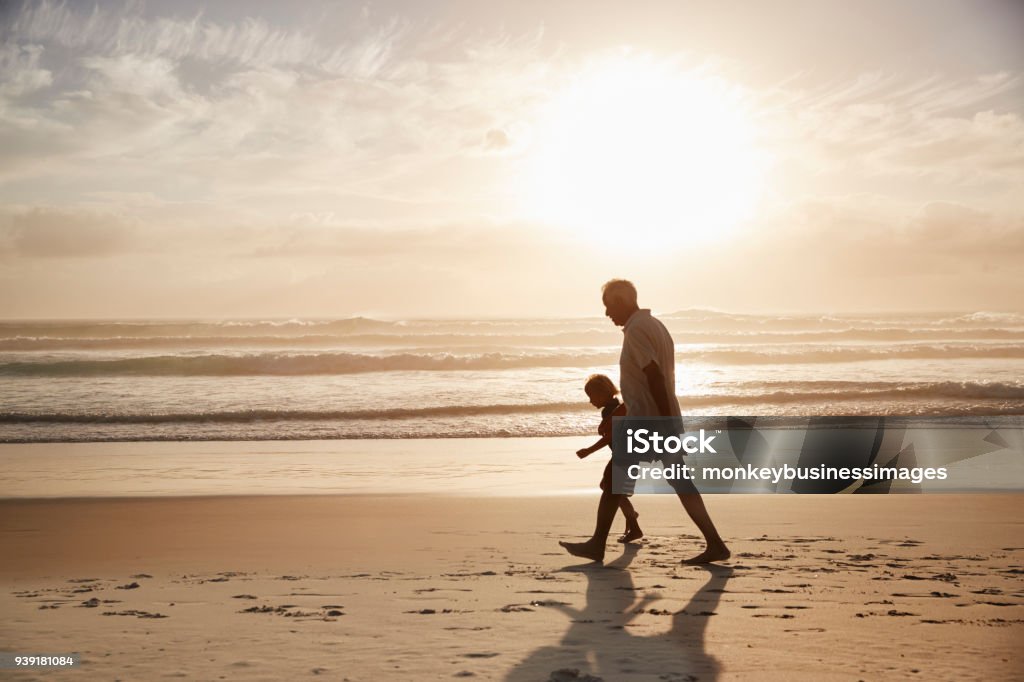 Silhouette Of Grandfather Walking Along Beach With Grandson Grandfather Stock Photo