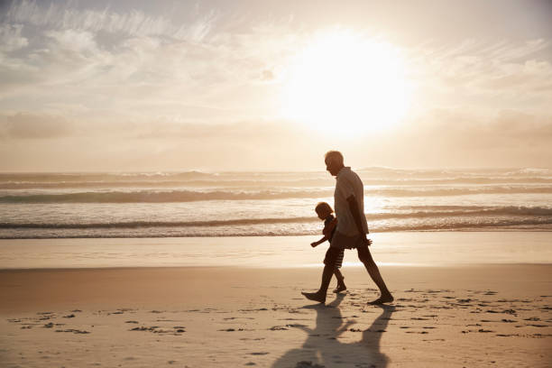 силуэт деда, гуляя по пляжу с внуком - grandparent grandfather walking grandchild стоковые фото и изображения