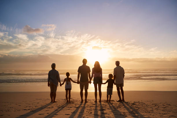 rückansicht des multi-generationen-familie silhouette am strand - hände halten fotos stock-fotos und bilder