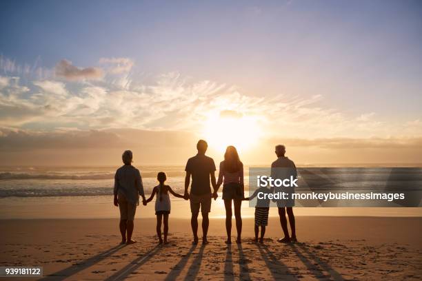 Rear View Of Multi Generation Family Silhouetted On Beach Stock Photo - Download Image Now