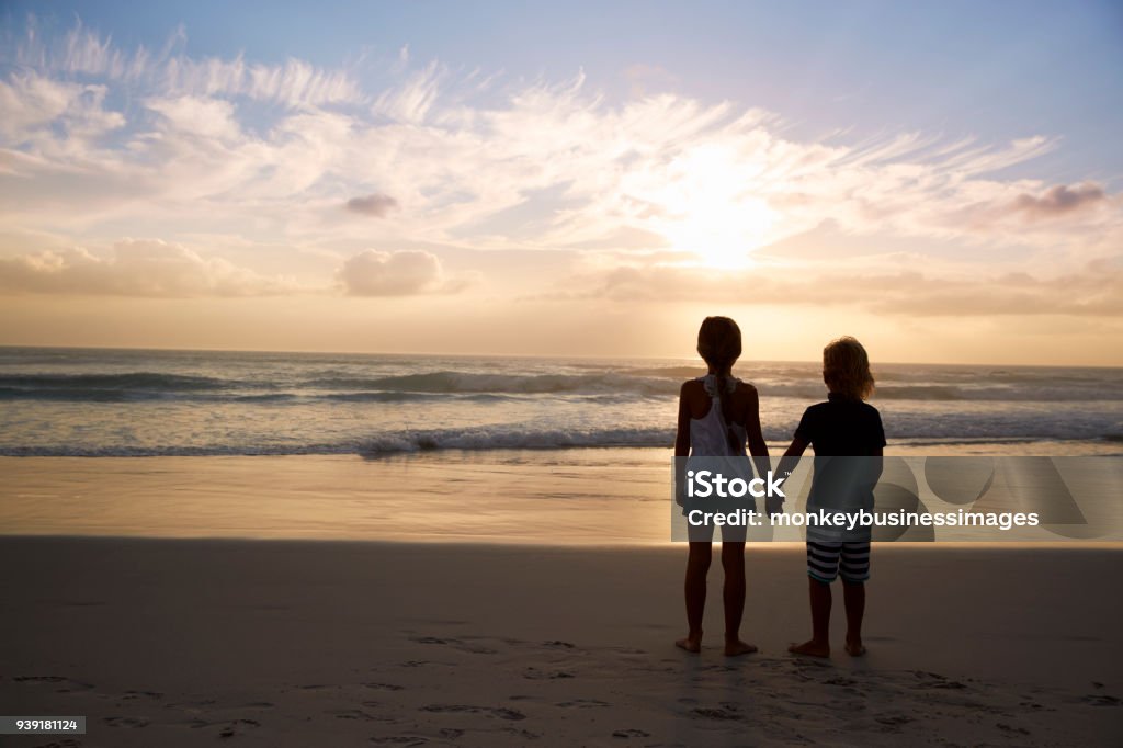 Vue arrière des enfants tenant par la main, que se découpant sur la plage - Photo de Enfant libre de droits