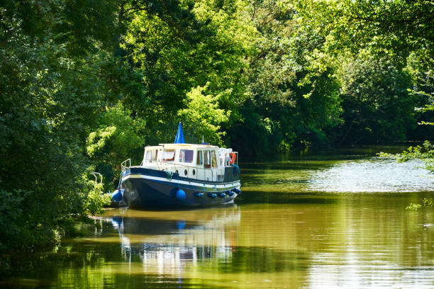Houseboat shore canal Houseboat anchors on the shore of a canal with trees in summer houseboat photos stock pictures, royalty-free photos & images